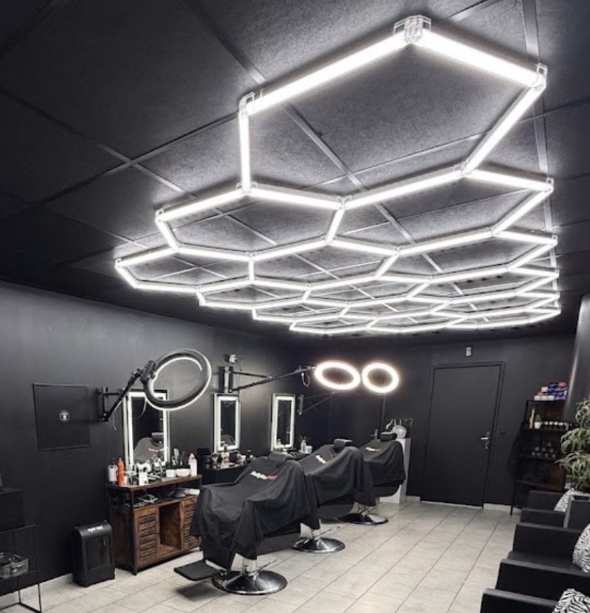 Intérieur du salon Le S Barber à Masnières : plafond LED en nid d'abeille et fauteuils de barbier